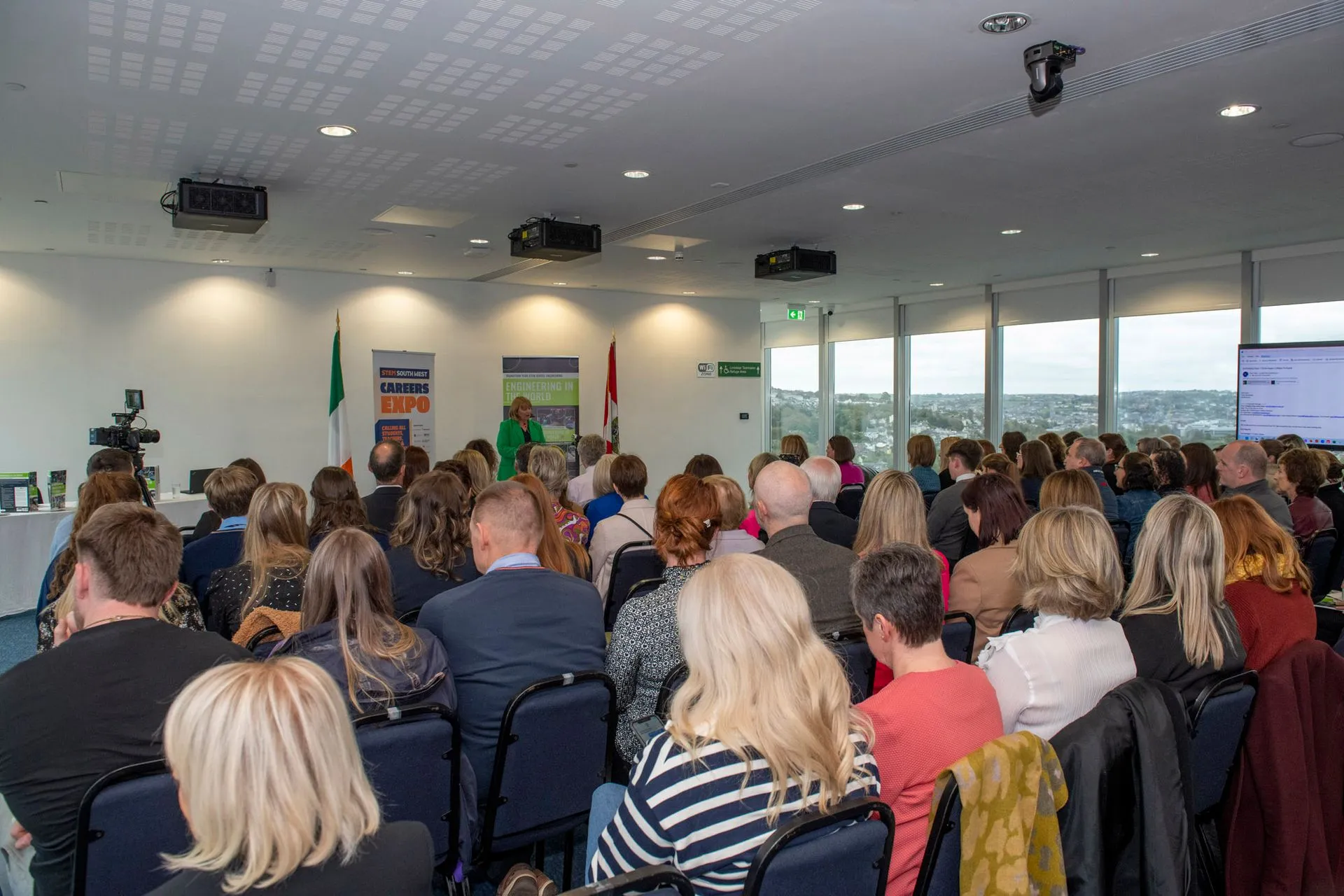 A full audience facing the stage at the launch, seen from the back of the room
